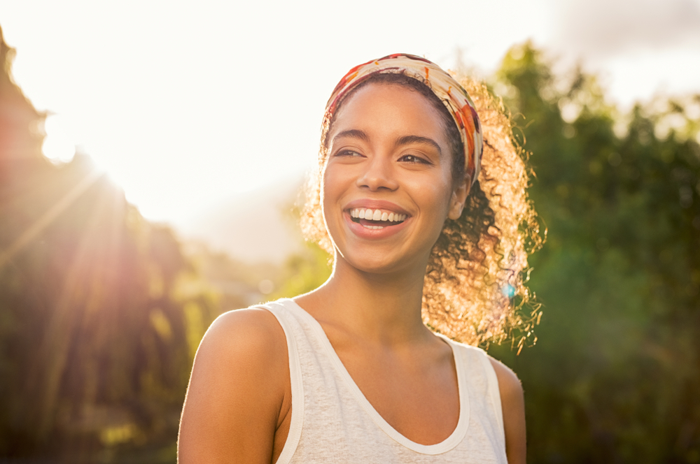 A woman smiling outdoors in evening sunlight