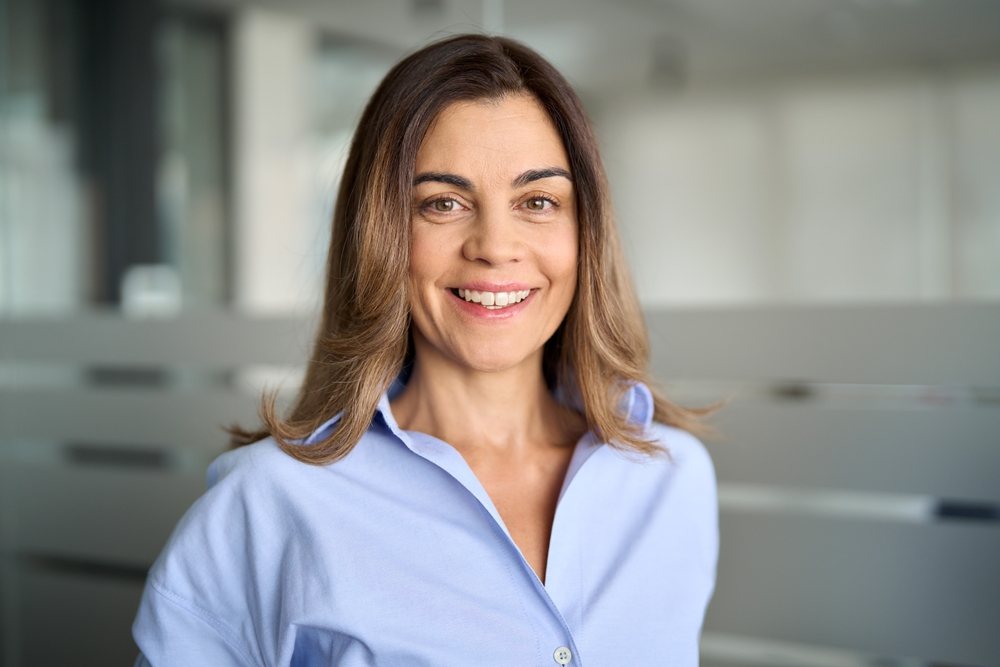 A woman in a pale blue shirt smiling