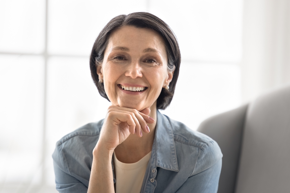 A woman in a denim shirt resting her chin on her hand