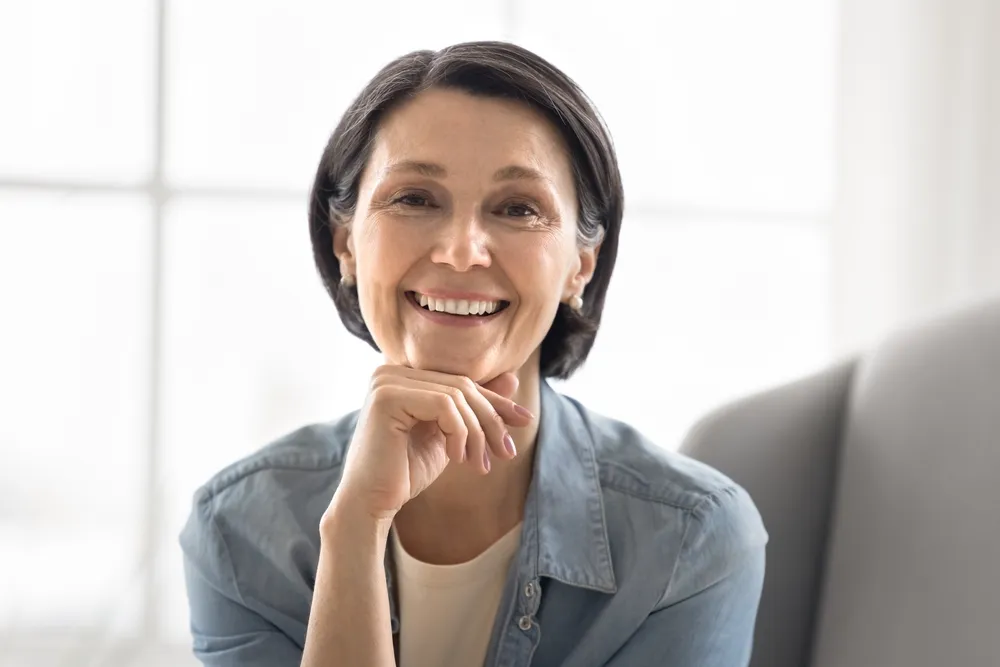 A woman in a denim shirt resting her chin on her hand