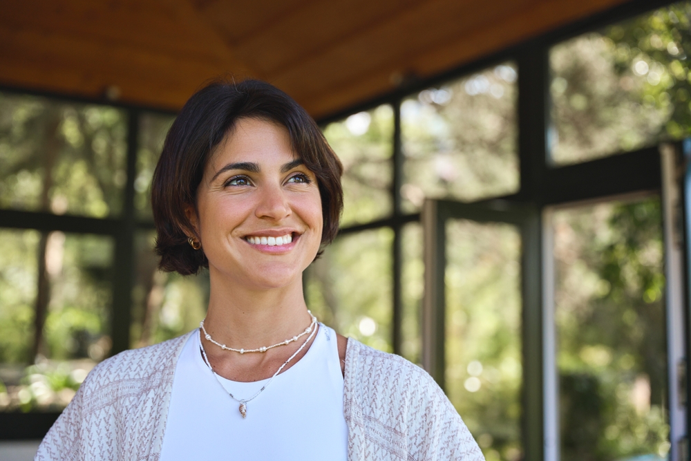 A woman in a garden room, smiling and looking up