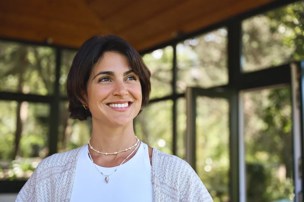 A woman in a garden room, smiling and looking up