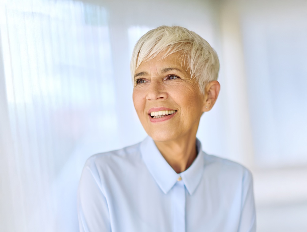 A woman with short silver hair in a pale blue shirt, smiling