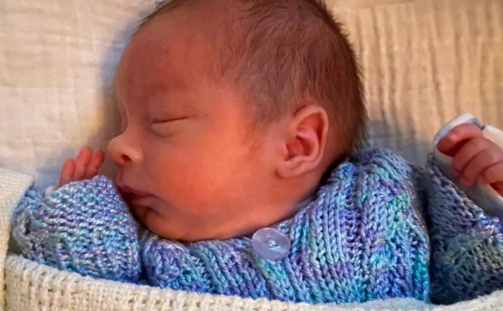 A sleeping newborn in a knitted cardigan