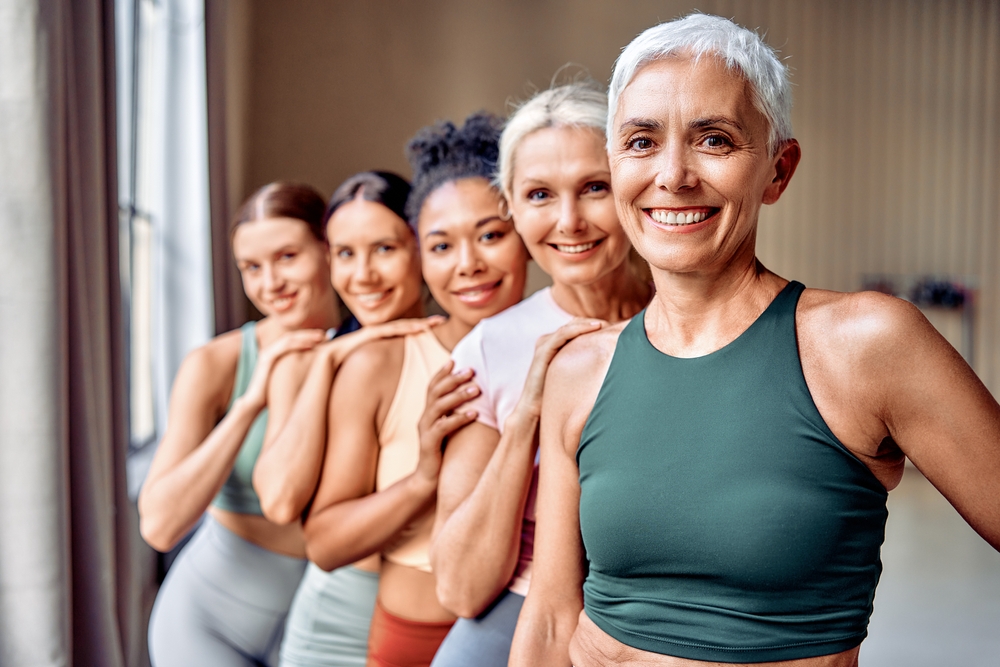 Five women of different ages standing together, smiling